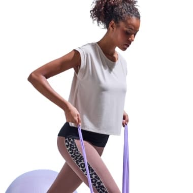 Frau in Sportkleidung trainiert mit lila Fitnessbändern und Gymnastikball.