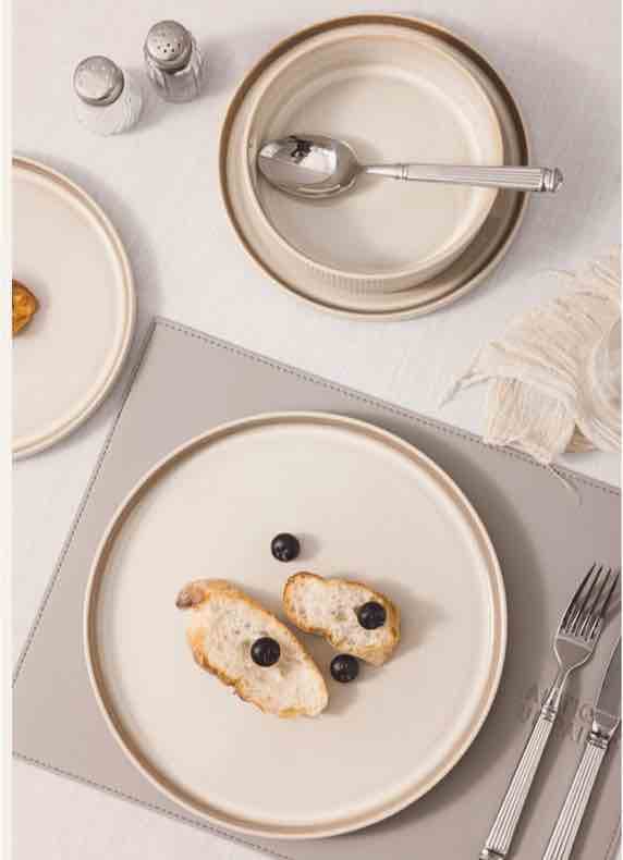 Großer Teller mit zwei Brotscheiben und Beeren, daneben Besteck, Schale mit Löffel sowie Salz- und Pfefferstreuer