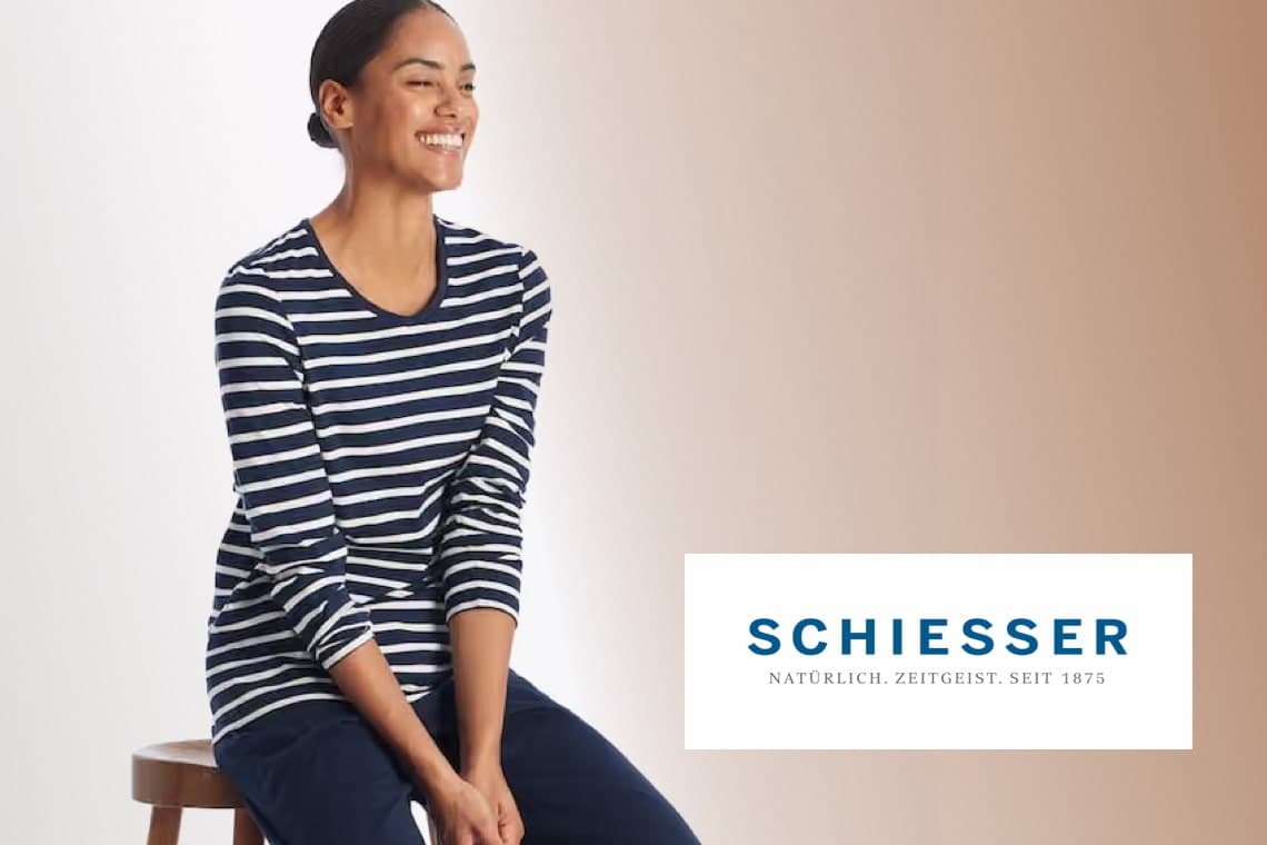 Schiesseer – Frau im dunkel gestreiften Langarmshirt sitzt lächelnd auf einem Hocker vor hellem Hintergrund