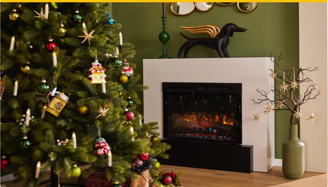 Weihnachtlich geschmückter Baum neben einem modernen Kamin mit Dekorationen auf der Kaminablage und einem grünen Hintergrund.