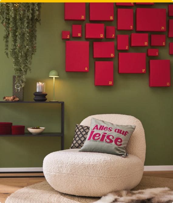 Alles auf leise – gemütlicher Sessel mit Kissen, grünes Wandregal, rote Wanddekoration mit Zahlen in grünem Raum