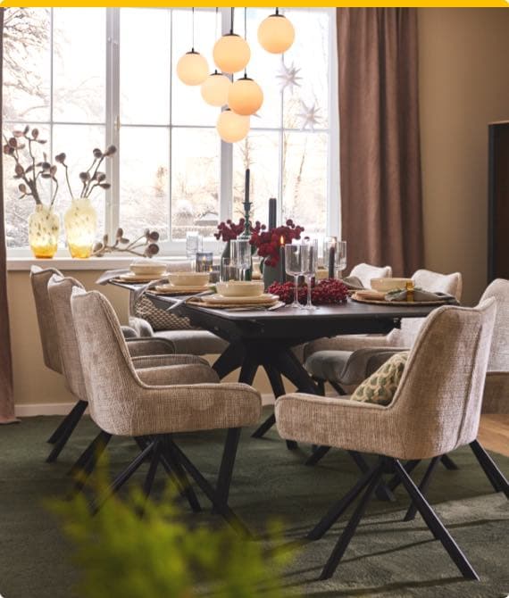 Esszimmer mit Tisch, gedeckt für sechs Personen, beige Stühle, große Fenster, dekorative Lampen und Pflanzen