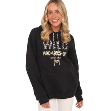 Frau trägt schwarzen Hoodie mit Aufdruck "WILD" und weißen Kordeln, weiße Hose.