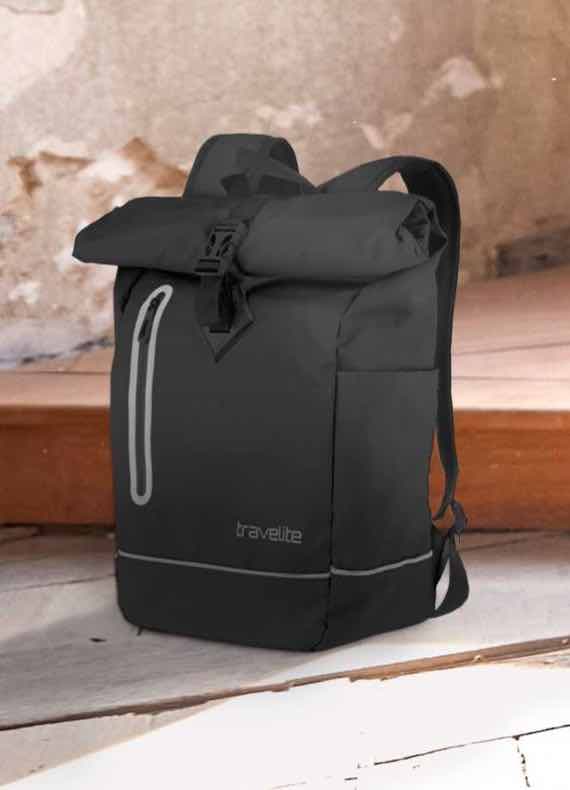 Schwarzer Rucksack mit reflektierenden Details und Rolltop-Verschluss auf Holzoberfläche vor rustikalem Hintergrund.