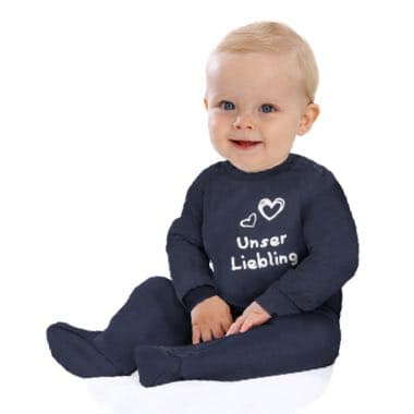 Baby in dunkelblauem Strampler mit Aufschrift "Unser Liebling" und Herzmotiven sitzt auf weißem Boden.