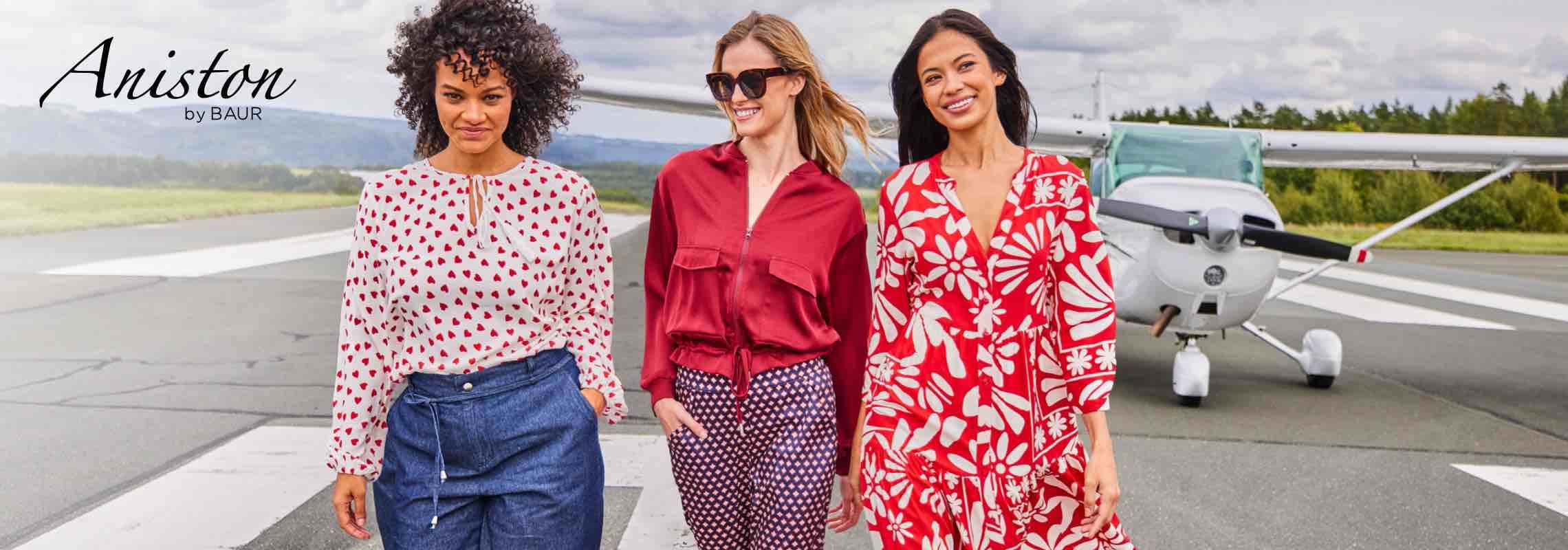 Aniston by BAUR – Drei Frauen in gemusterten Outfits vor einem Flugzeug auf einer Landebahn