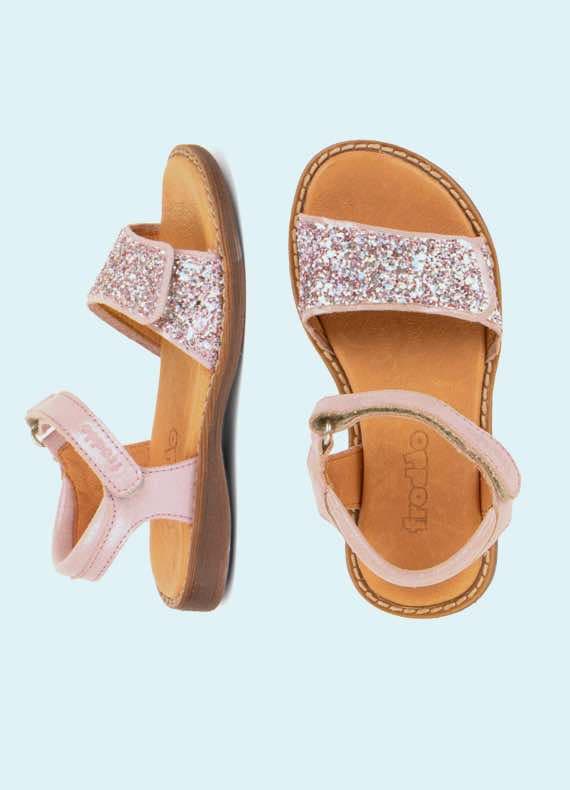 Rosa Kindersandalen mit glitzernden Riemen, von oben vor hellblauem Hintergrund fotografiert