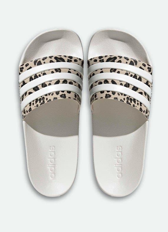 Weiße Slides von oben mit drei Streifen und gemustertem Riemen, adidas Schriftzug im Fußbett sichtbar