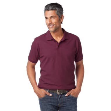Mann in bordeauxfarbenem Poloshirt und Jeans steht mit Händen in den Hosentaschen und blickt zur Seite