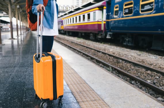 Frau mit Koffer am Bahnsteig