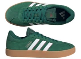 Ein Paar grüne Sneakers von Adidas mit weißen Streifen und einer braunen Gummisohle. Die Schuhe haben ein klassisches Design aus weichem Material und sind ideal für lässige Outfits.
