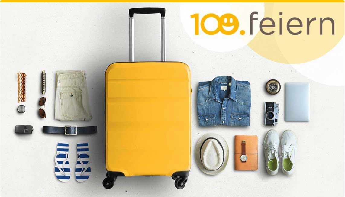 100. feiern – Gelber Rollkoffer und Reiseutensilien wie Kleidung, Schuhe, Hut, Kamera und Laptop auf hellem Hintergrund