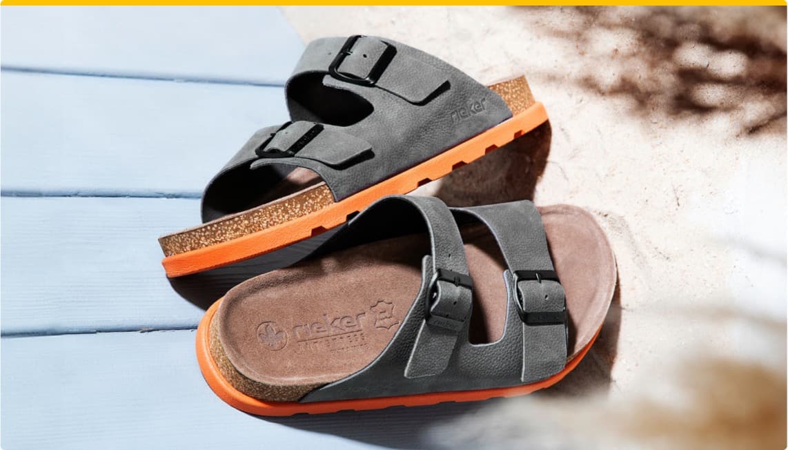 Stylische Rieker-Pantoletten in Grau mit orangefarbener Sohle, auf einem hellen Untergrund präsentiert.