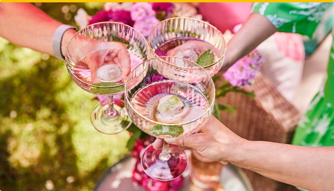 Drei Gläser mit erfrischenden Cocktails, dekoriert mit Minze, werden fröhlich angestoßen