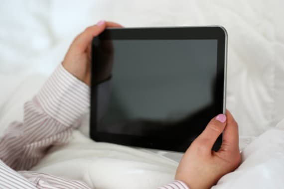 Person hält schwarzen Tablet-PC mit beiden Händen.