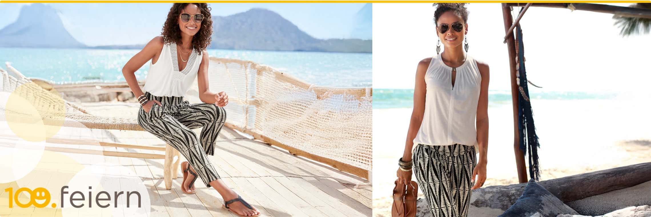 100. feiern – Frau in weißem Top und gemusterten Hosen am Strand mit Meerblick im Hintergrund