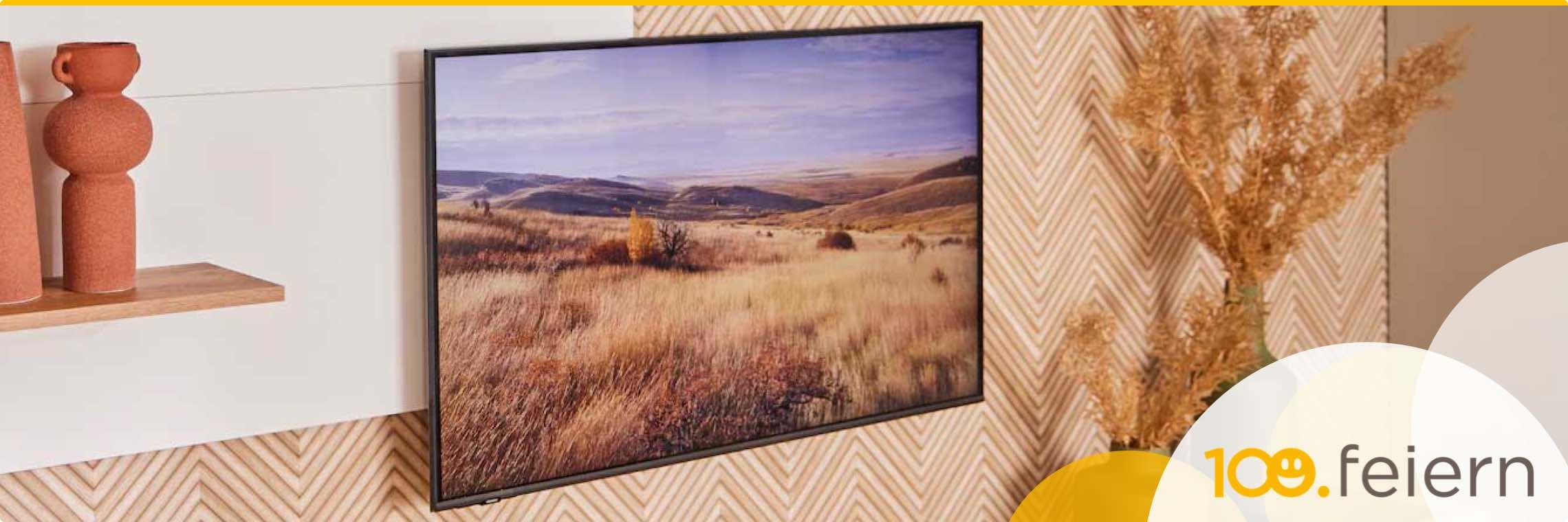 100. feiern – Wohnzimmer mit Landschaftsbild an der Wand, zwei Vasen auf einem Regal und Trockenblumen in einer Ecke