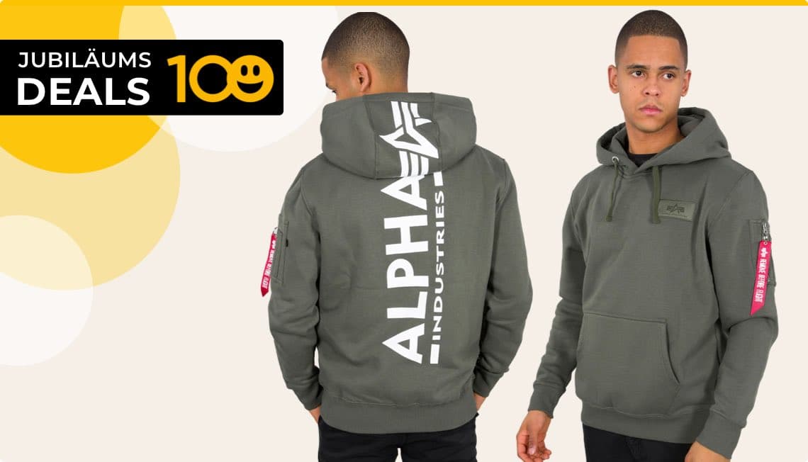 Jubiläums Deals 100 – Mann in grauem Hoodie mit Alpha Industries Logo auf Rücken und rotem Anhänger am Ärmel