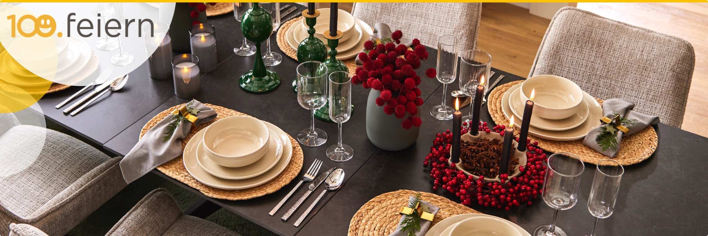 100. feiern – Festlich gedeckter Tisch mit Geschirr, Gläsern, Kerzen und Dekorationen in Rot und Grün