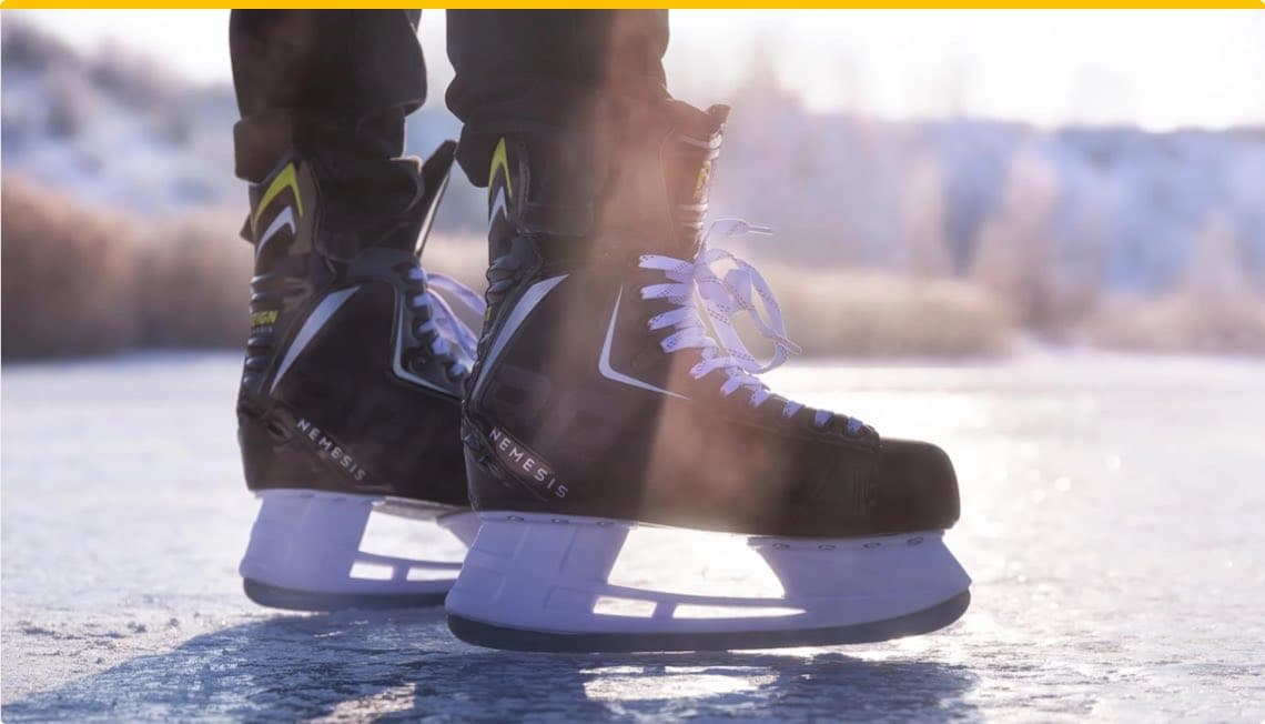 Schwarze Eishockey-Schlittschuhe mit weißer Kufe und gelben Akzenten auf einer eisigen Oberfläche.