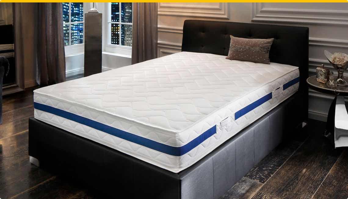 Modernes Schlafzimmer mit gepolstertem Bett und weißer Matratze mit blauen Streifen, Fenster mit Stadtblick im Hintergrund