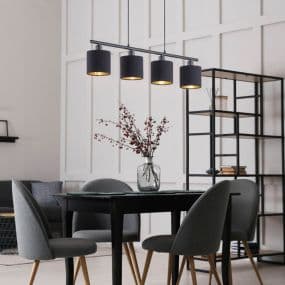 Esszimmer mit schwarzem Tisch, grauen Stühlen und schwarzer Hängelampe. Vase mit Zweigen auf dem Tisch.