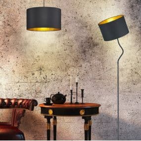 Schwarzer Lampenschirm über einem antiken Tisch mit Teekanne und Kerzenständern, daneben eine Stehlampe.