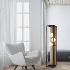 Modernes Wohnzimmer mit grauem Sessel und stilvoller Stehlampe mit drei Kugellichtern vor einem Fenster.