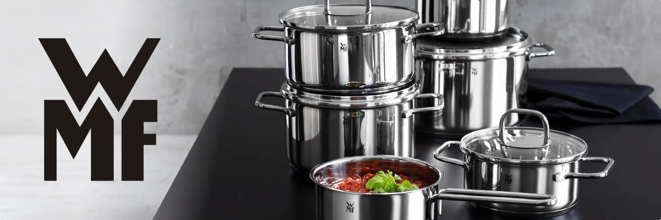 WMF Logo – Edelstahlkochtöpfe auf schwarzem Tisch, ein Topf mit Tomatensauce und Basilikum