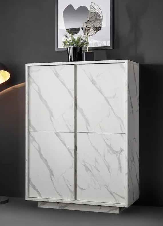 Weißer Schrank mit grauen Marmorstreifen, zwei Türen, vor dunkler Wand. Oben darauf Pflanzen und dekorative Elemente.