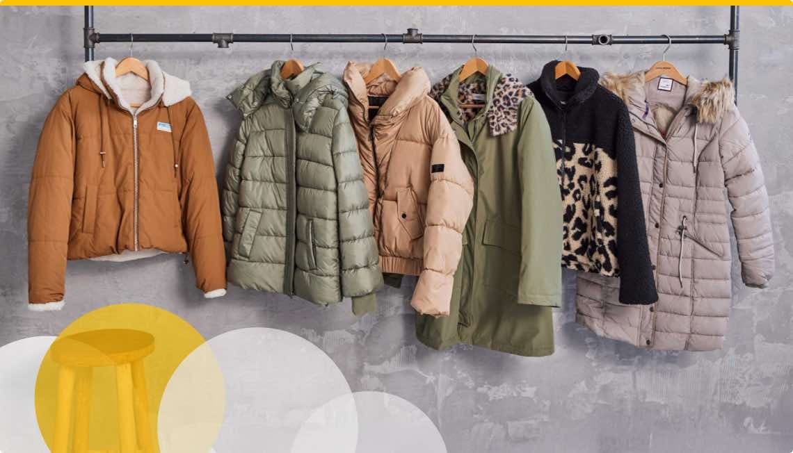 5 Winterjacken auf Holzkleiderbügeln, darunter ein leerer Holzhocker mit gelben und weißen Kreisen.