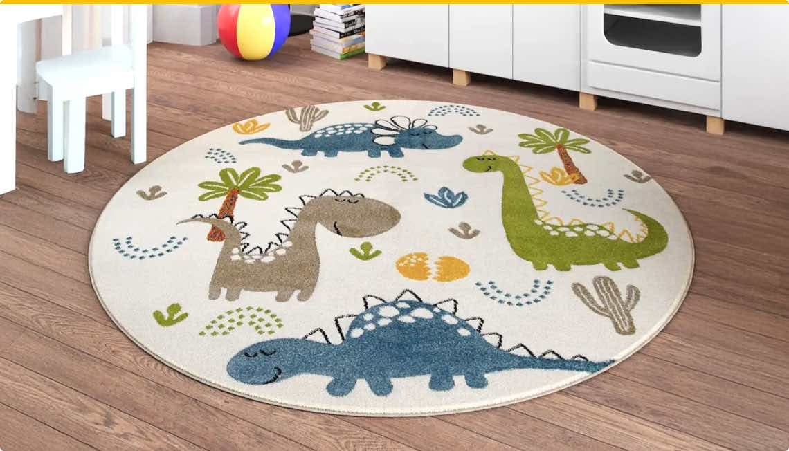 Runder Teppich mit bunten Dinosaurier-Motiven auf Holzboden in Kinderzimmer, weißer Stuhl und bunte Spielbälle im Hintergrund.