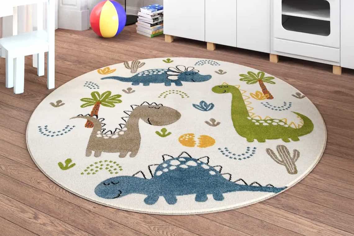 Runder Teppich mit bunten Dinosaurier-Motiven im Kinderzimmer auf Holzboden.