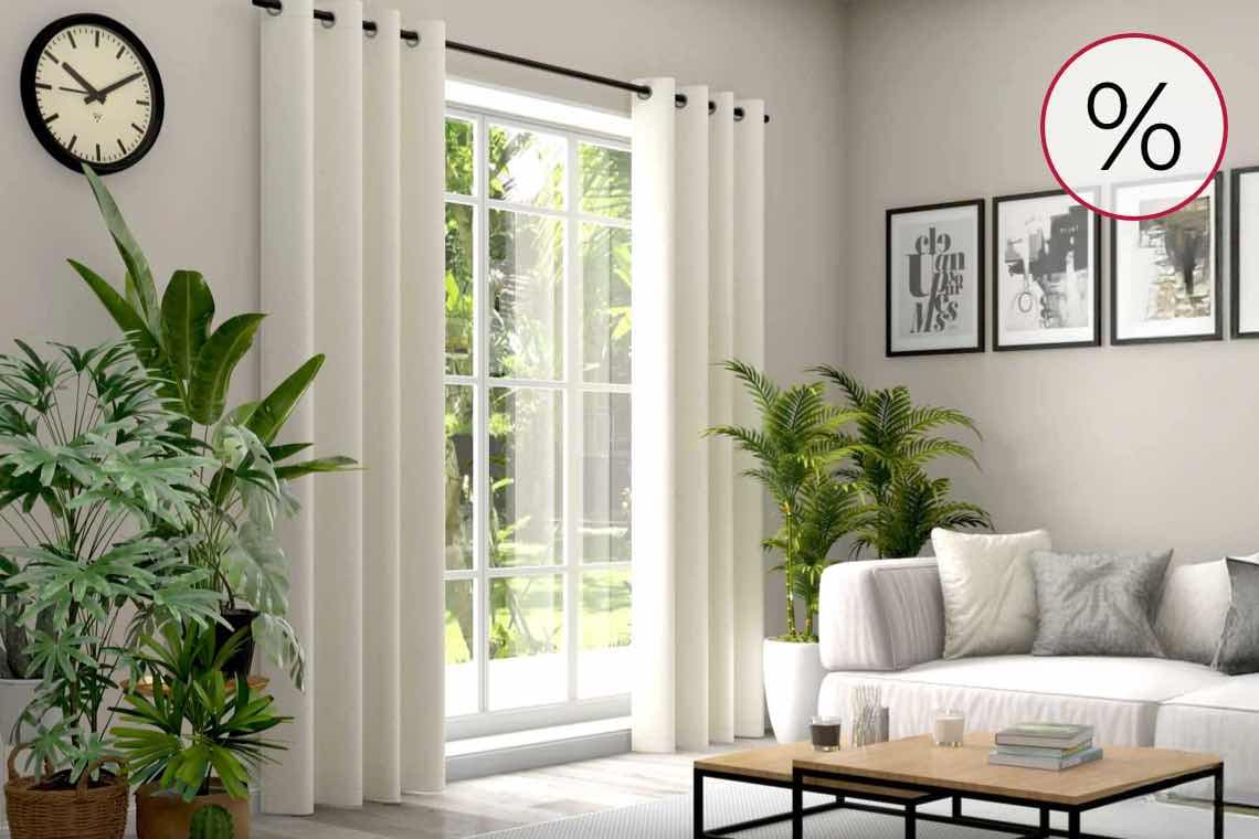 Prozentzeichen in Kreis – Wohnzimmer mit großen Pflanzen, weißen Vorhängen und Sofa vor Fenster, Bilder an der Wand