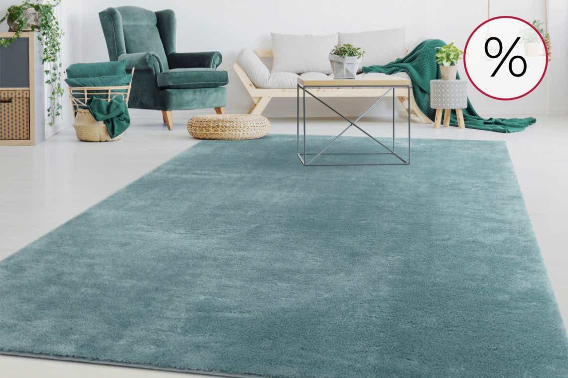 % – Wohnzimmer mit grünem Sessel, Korb und blauem Teppich