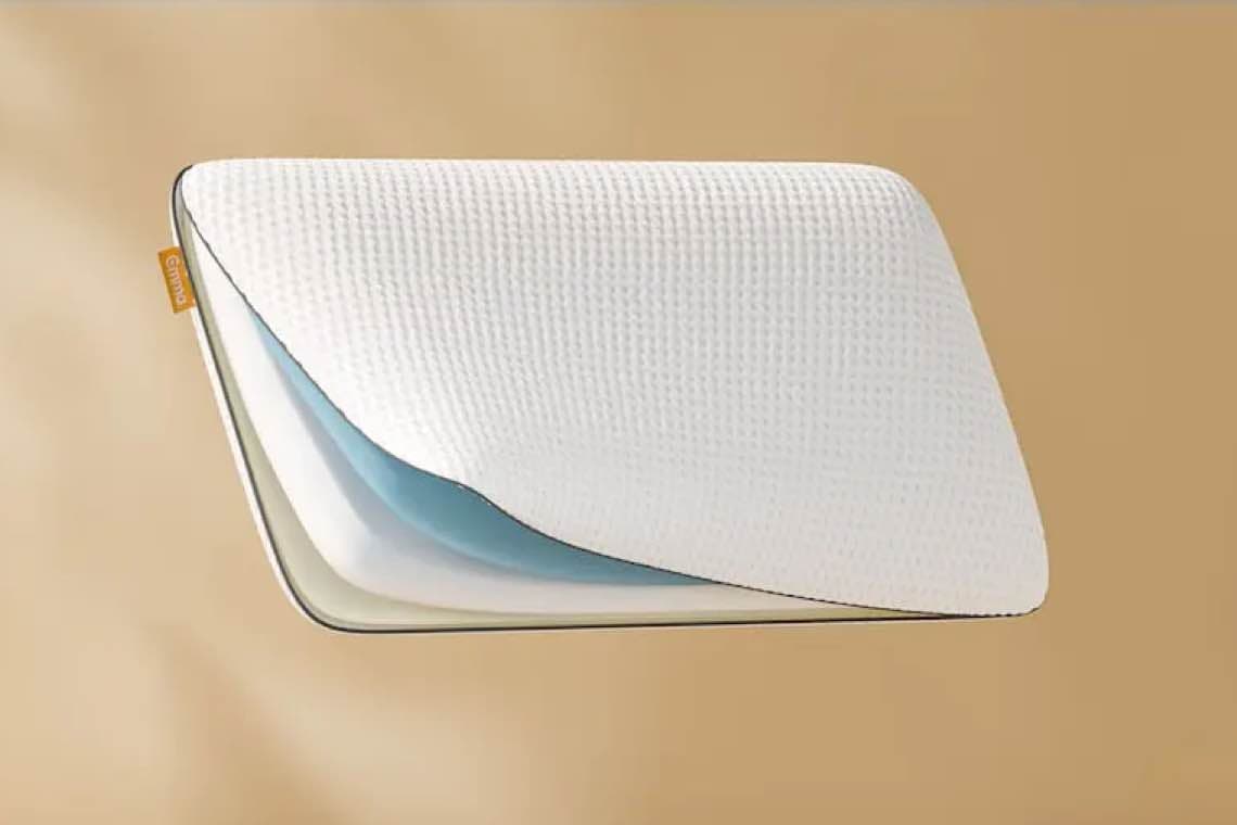 Ergonomisches Kissen von Emma mit weißem Bezug und mehreren Schichten, darunter eine blaue Schicht.