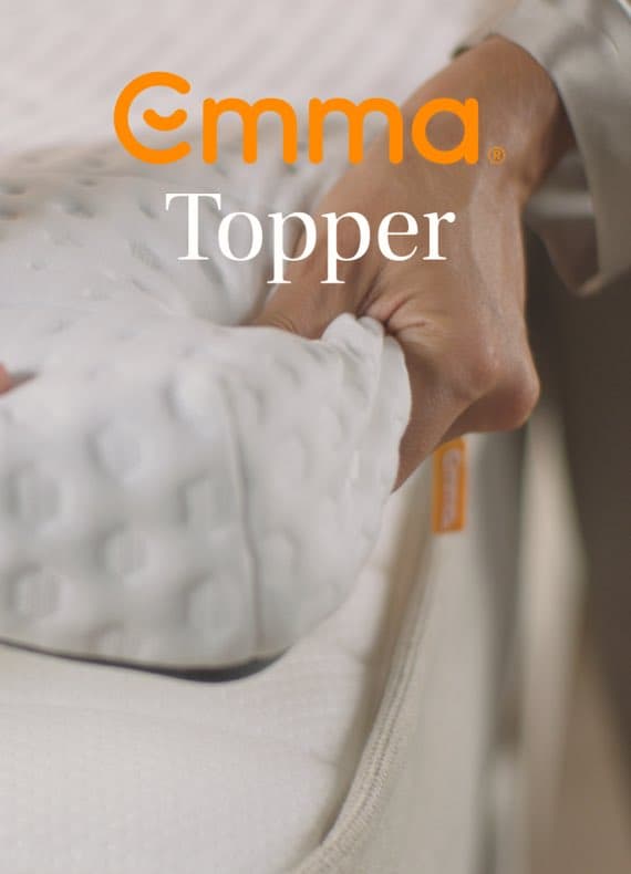 Emma Topper – Hand richtet weißen Matratzentopper auf Bett