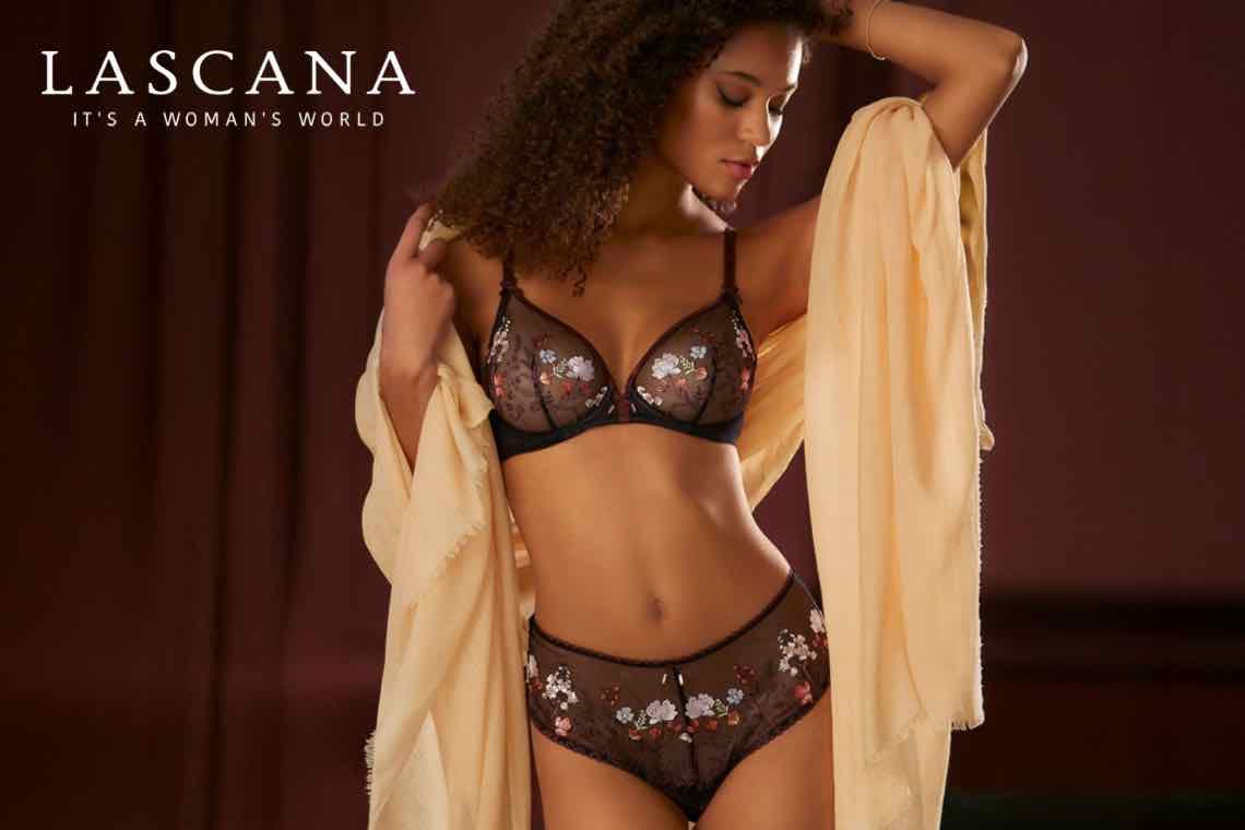 LASCANA – Frau in schwarzer Unterwäsche mit Blumenmuster und gelbem Tuch.