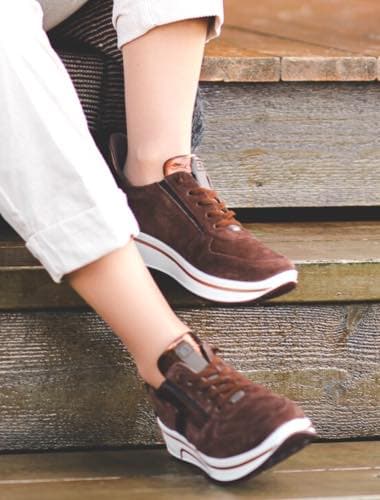 Person mit braunen Sneakers und weißen Hosenbeinen sitzt auf einer Holztreppe.