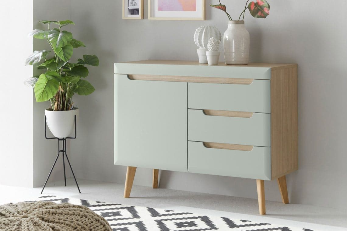 Mintfarbene Kommode mit drei Schubladen und Pflanze in weißem Topf auf schwarzem Gestell daneben.