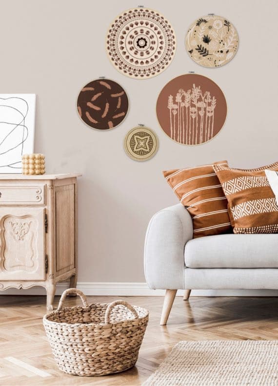 Wohnzimmer mit dekorativen Wandtüchern, beigem Sofa, gemusterten Kissen und Korb auf Holzboden.