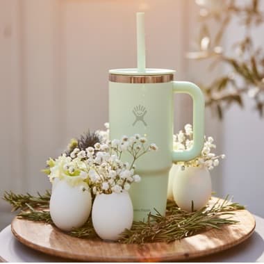 Trinkbecher umringt von kleinen Dekovasen auf einem Tablett