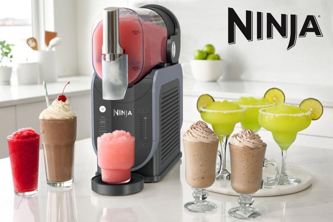 Ninja Eisgetränke-Maschine auf Küchenarbeitsplatte, umgeben von bunten Slushies, Shakes und Margaritas in Gläsern