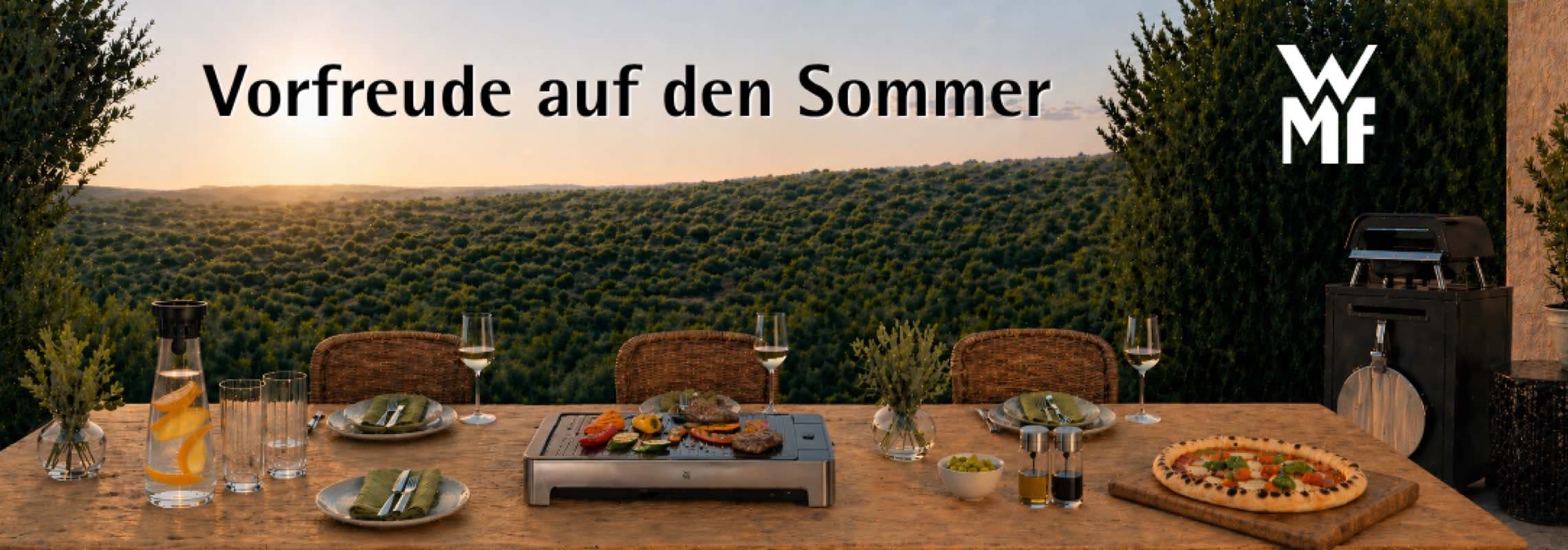 Vorfreude auf den Sommer – gedeckter Gartentisch mit WMF Grill, Pizza und Getränken vor weiter grüner Hügellandschaft