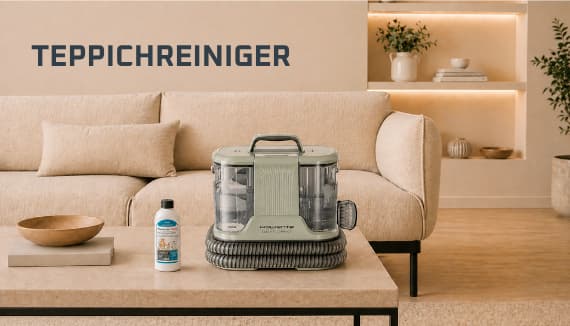 TEPPICHREINIGER – Teppichreinigergerät und Reinigungsmittel stehen auf Couchtisch vor beigem Sofa im Wohnzimmer