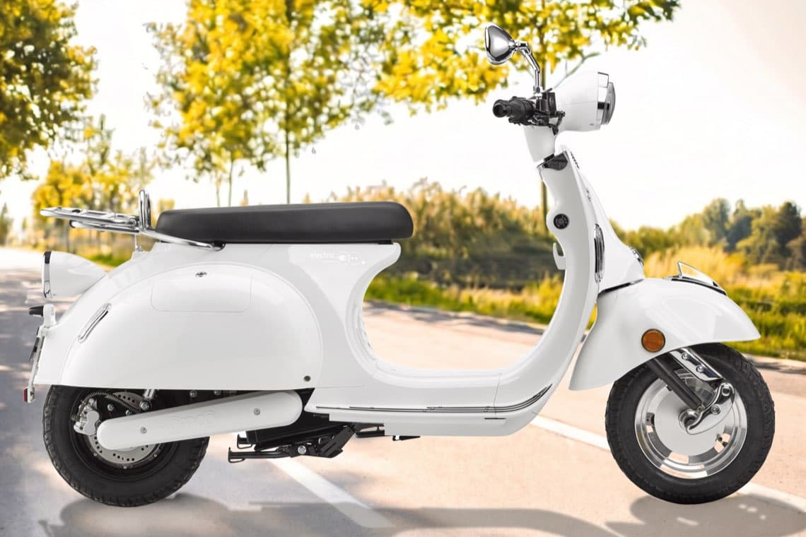 Weißer Retro-Roller steht auf leerer Landstraße mit grünen Bäumen im Hintergrund