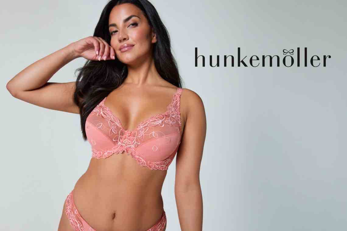 Hunkemöller – Frau in rosa besticktem BH und Slip steht seitlich und legt eine Hand an den Kopf