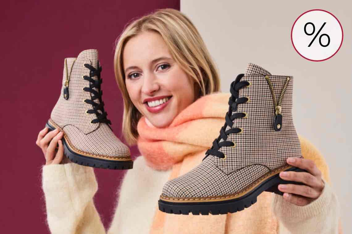 %-Zeichen Angebot – Person in hellgrüner Hose kniet, trägt weiße adidas Sneaker mit schwarzen Streifen und Logo