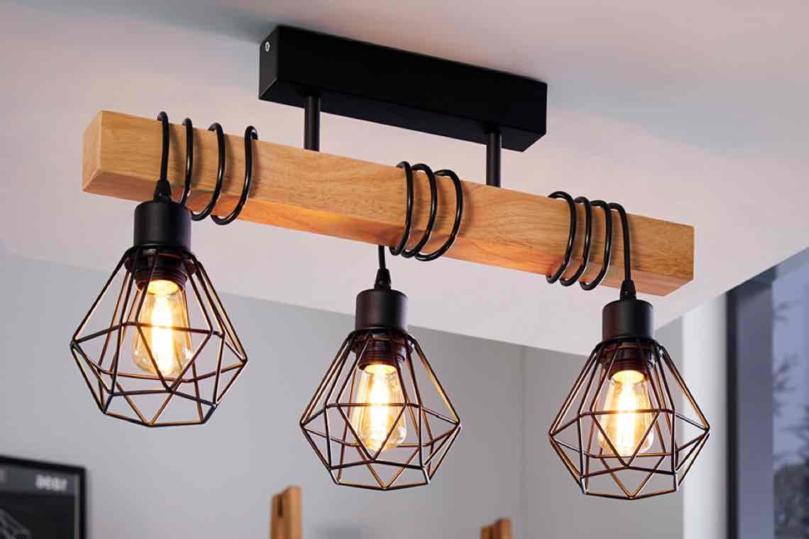 Deckenleuchte mit drei hängenden Käfiglampen an Balken, leuchtende Glühbirnen in geometrischen Fassungen