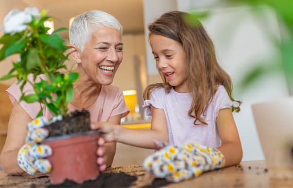 Frau und Kind, die eine Pflanze im Topf bearbeiten